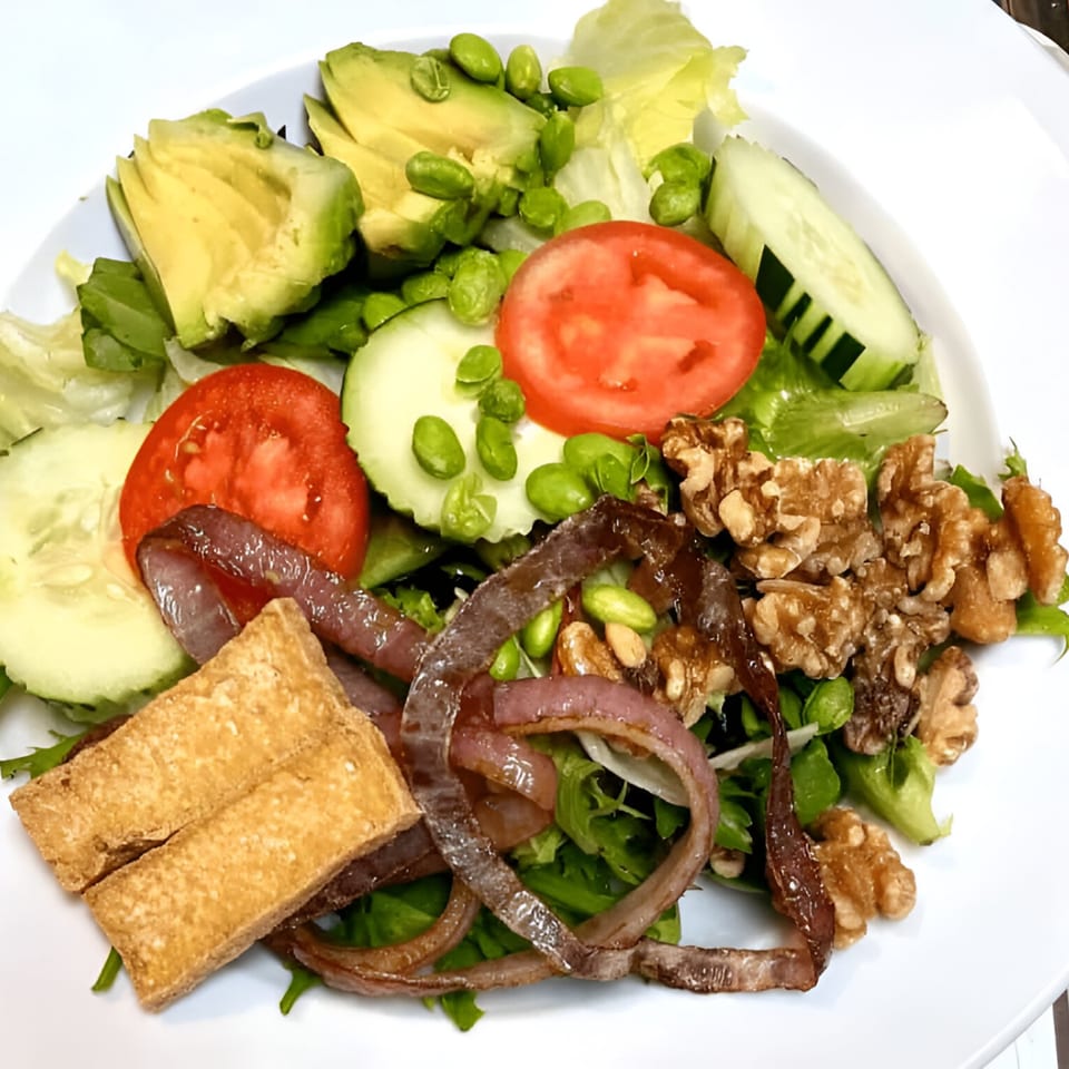 Thai Green House salad with avocado, cucumber, tomato, edamame, walnuts, fried tofu, and red onion.