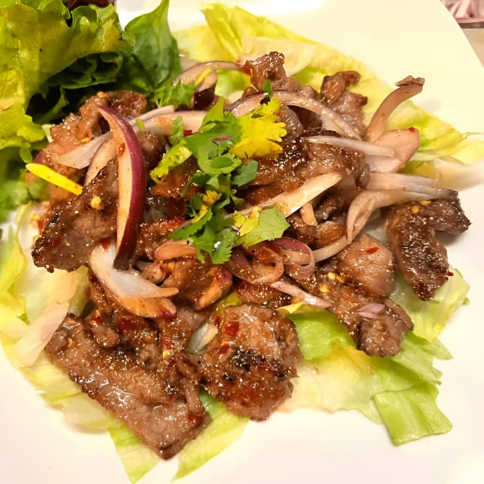 Thai Green House's spicy beef salad with red onions, cilantro, and chili flakes on lettuce.